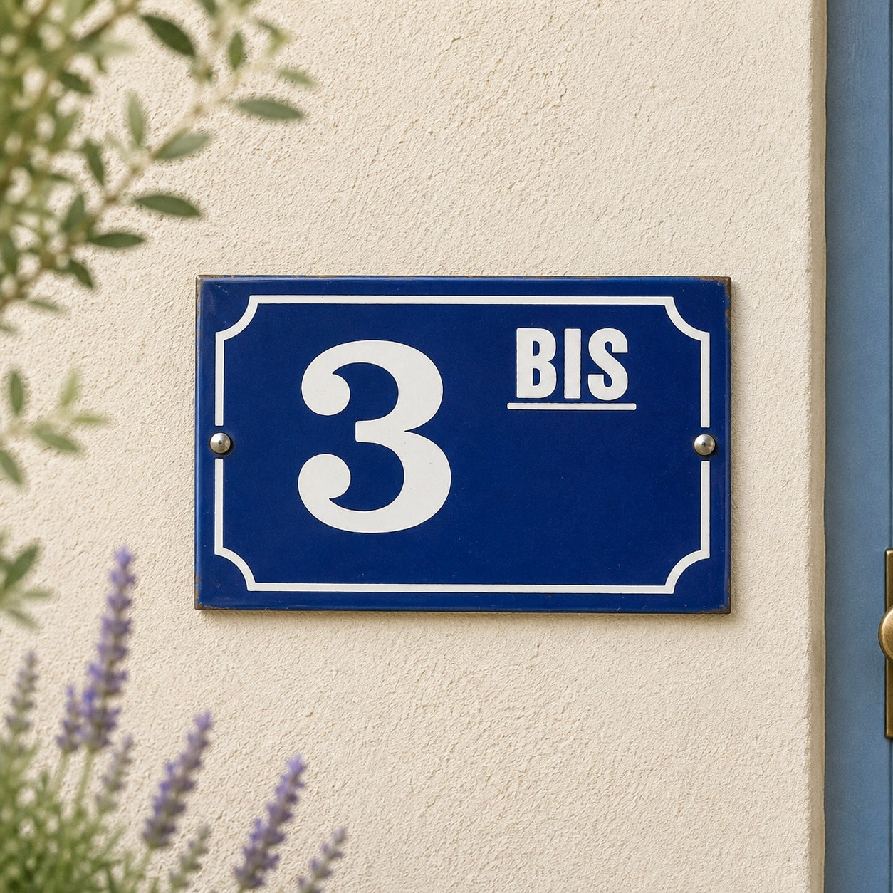 Blue house number sign with '3 BIS' on a beige wall with lavender and greenery.