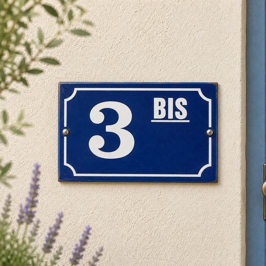 Blue house number sign with '3 BIS' on a beige wall with lavender and greenery.