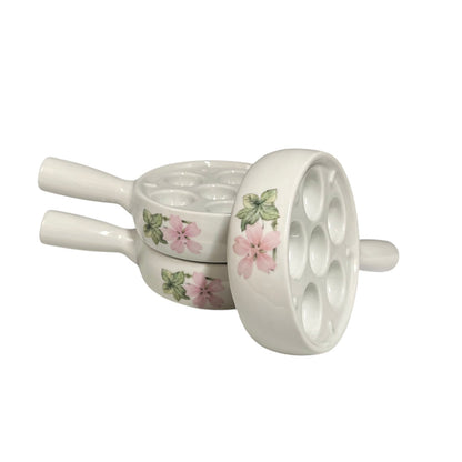 Three white porcelain escargot plates with pink floral designs, arranged on a plain white background