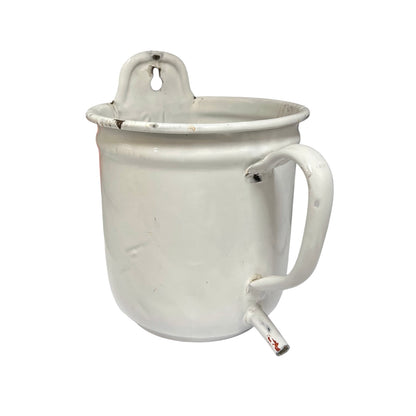 A vintage white enamel pot  with a side spout and a hanging loop on the rim, shown against a plain white background.