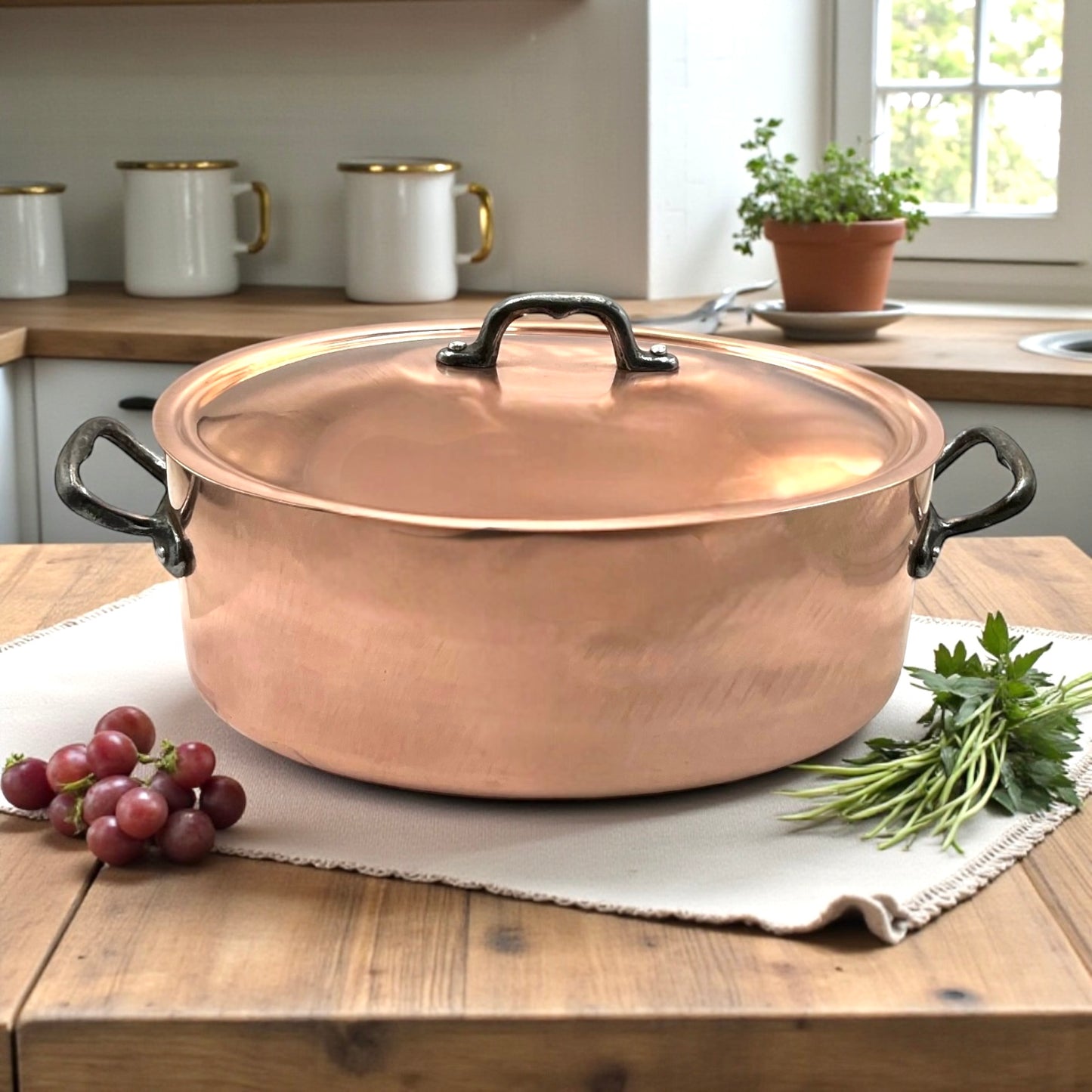 Copper pot with lid on a wooden table with grapes and herbs