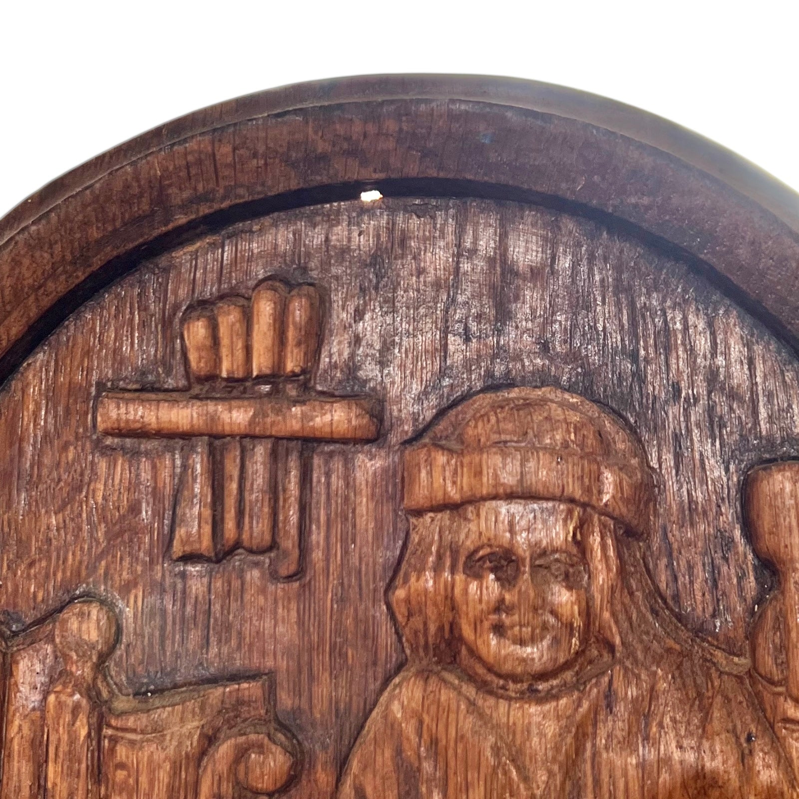 Wooden plaque with intricate carvings of a person and a bundle of sticks on a white background