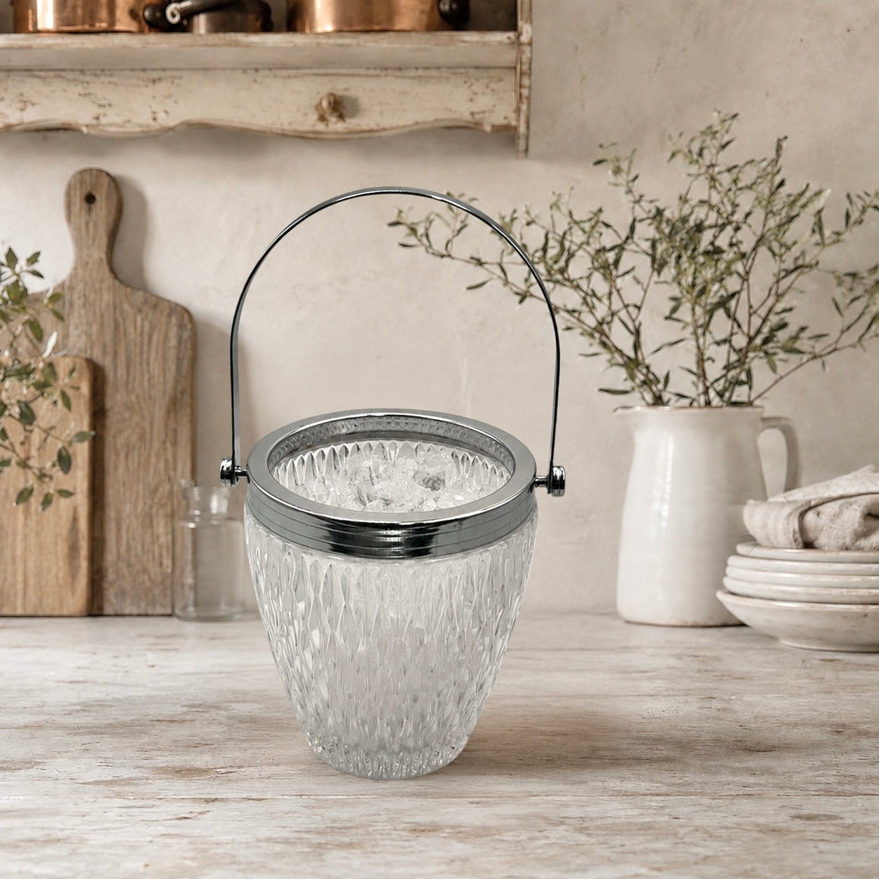 French vintage cut glass ice bucket with a chrome collar and handle on a counter top