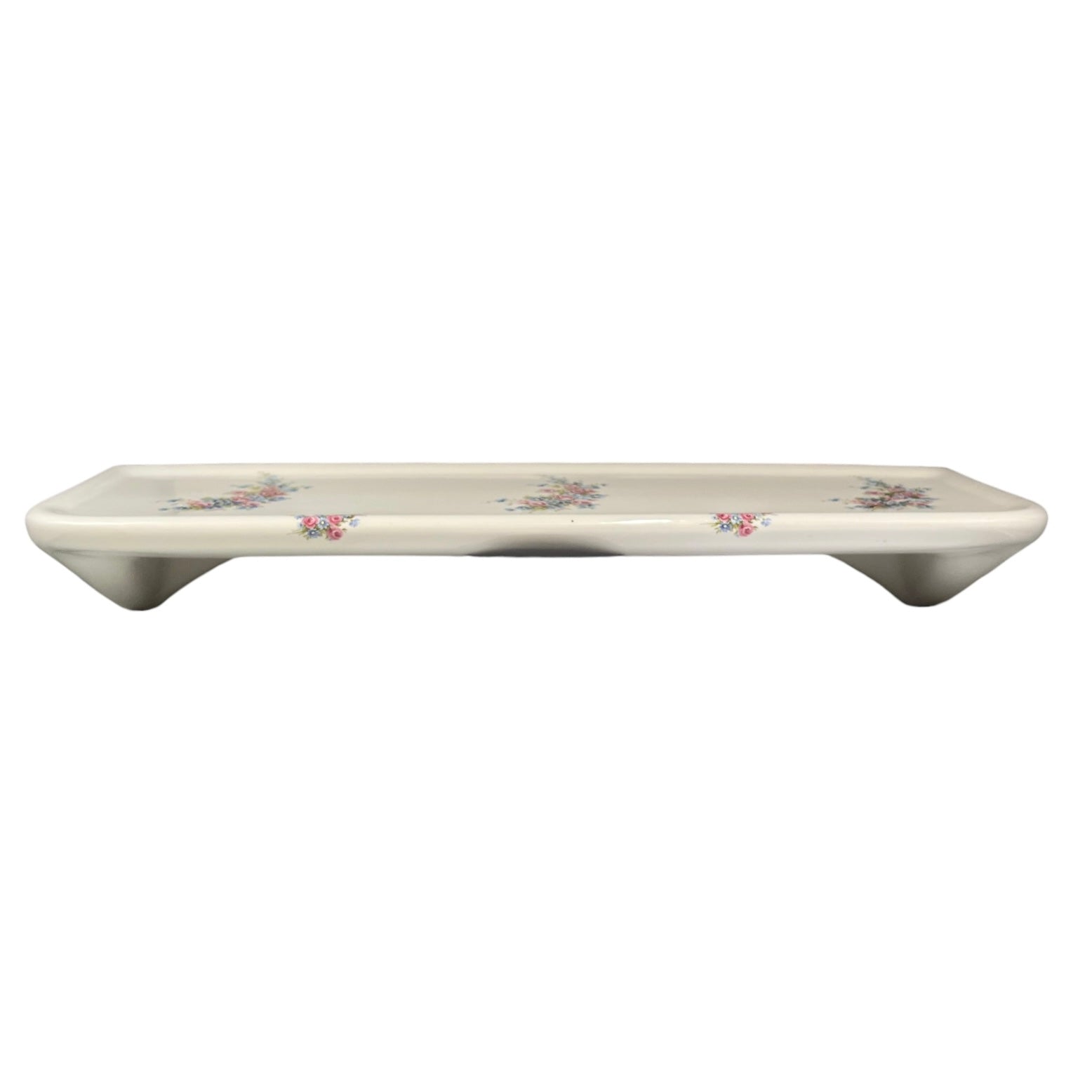 A rectangular ceramic shelf with a glossy white glaze and delicate pink floral patterns, shown against a plain white background.