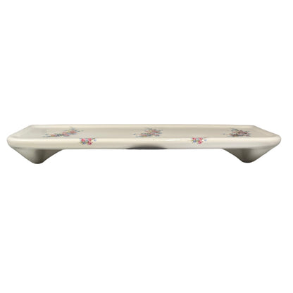 A rectangular ceramic shelf with a glossy white glaze and delicate pink floral patterns, shown against a plain white background.