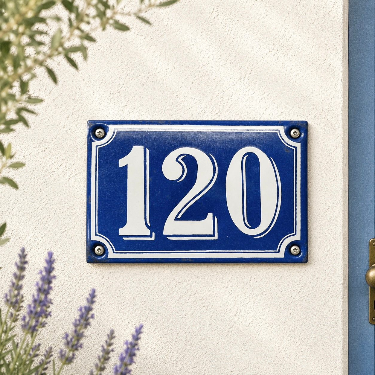 Blue house number plate with '120' on a white wall with plants around.