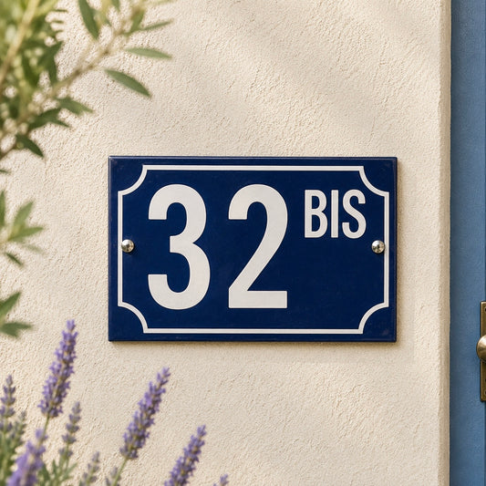 Blue house number sign with '32 BIS' on a beige wall with lavender plants.