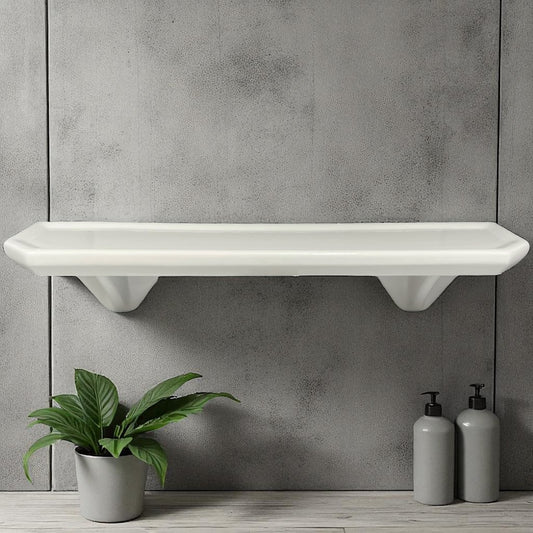 White wall-mounted shelf against a gray concrete wall with a plant and bottles below.