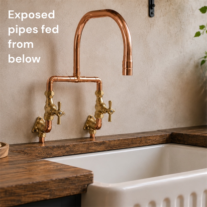 copper and brass kitchen mixer tap on a stone wall over a butler sink
