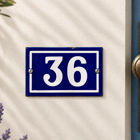 Blue and white house number '36' sign on a beige wall.