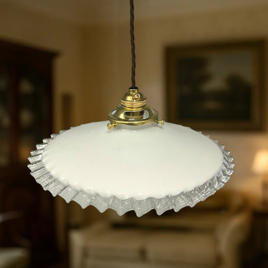 Vintage-style pendant light with white glass shade and gold fixture in a blurred indoor setting
