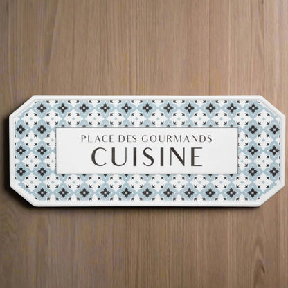 Decorative sign with patterned border and text on a wooden surface