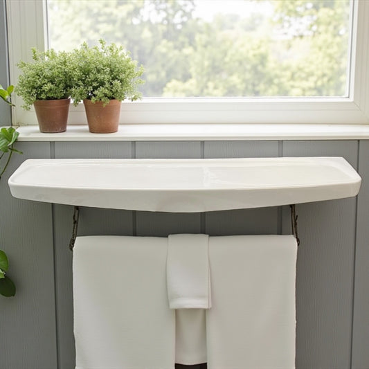 White curved shelf with towels underneath, plants on a windowsill in the background
