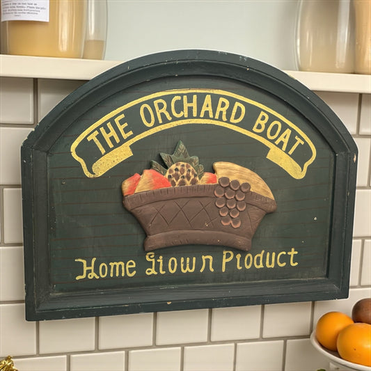 Decorative sign with 'The Orchard Boat' and 'Home Grown Product' text on a tiled wall.