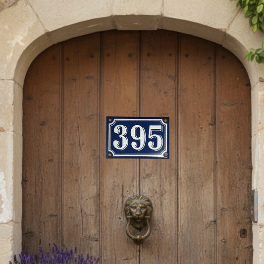Wooden door with a blue house number sign and lion knocker.