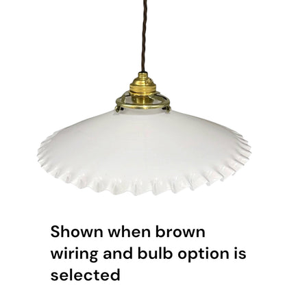 A white glass pendant light shade with a flared, scalloped edge and a brass-colored metal fixture, suspended by a brown cord against a white background. Text at the bottom reads, 'Shown when brown wiring and bulb option is selected'.