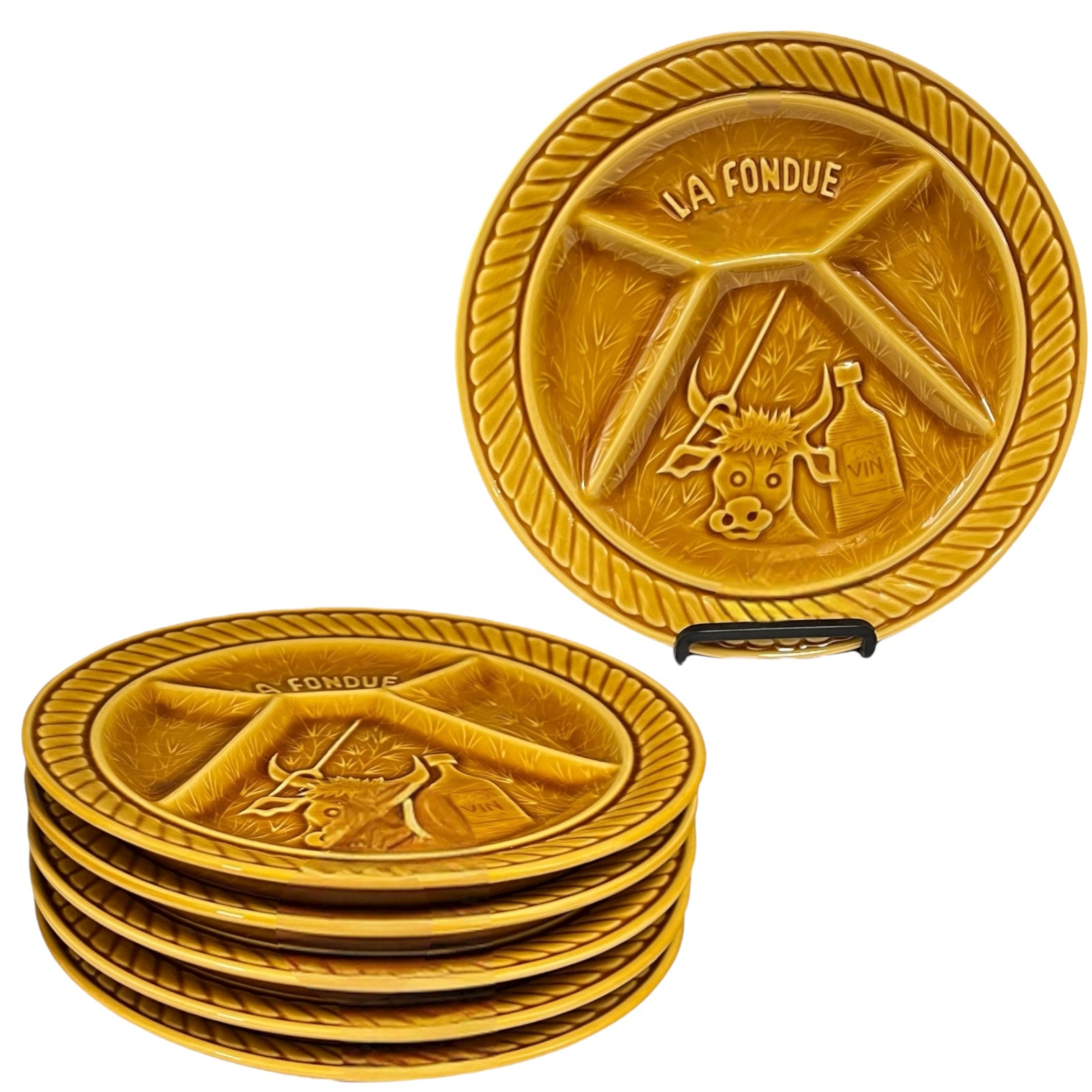 Set of orange brown fondue plates with embossed designs and 'La Fondué' text on a white background