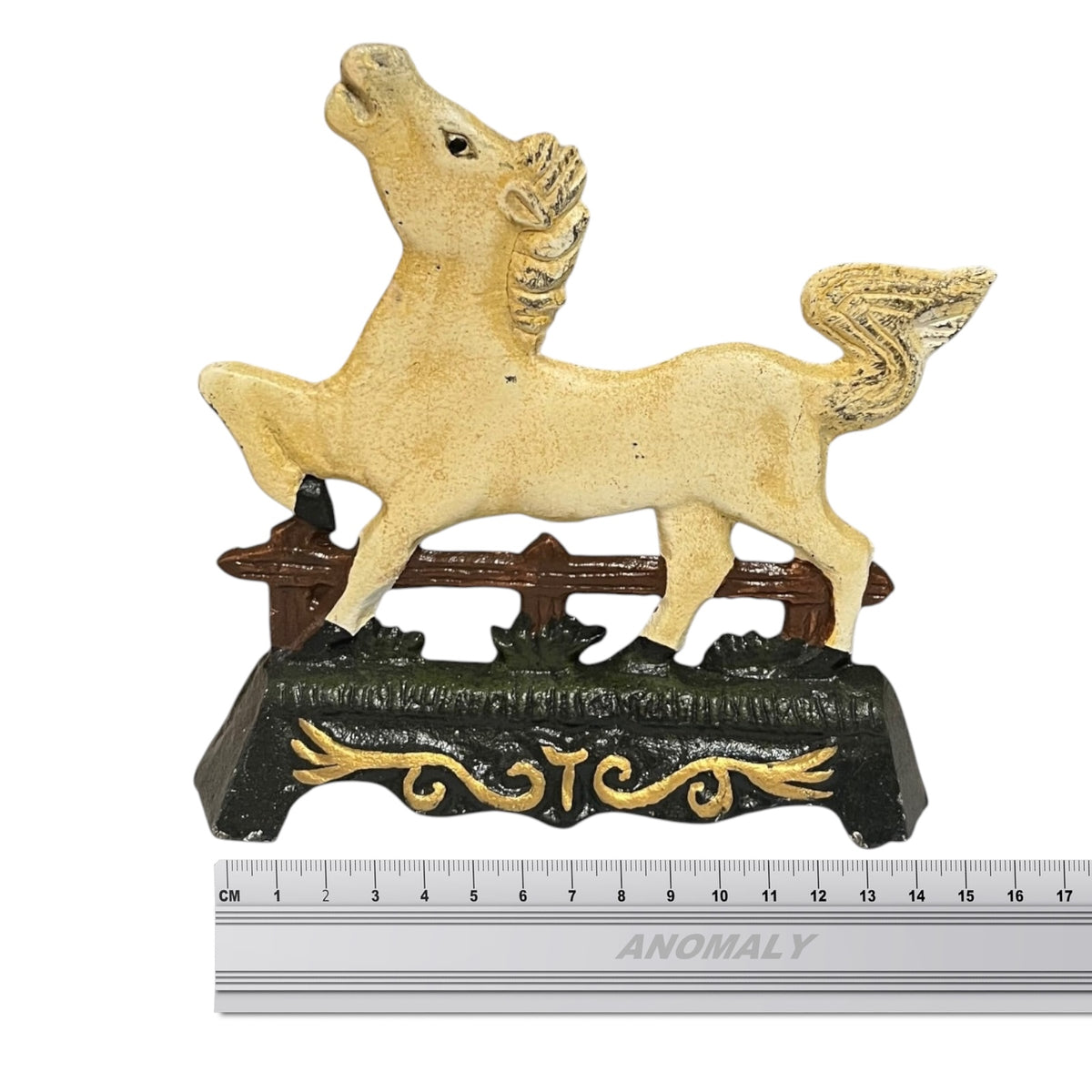 A decorative horse door stop with a cream-colored body and golden-brown mane and tail, standing on a dark base with gold scrollwork, shown against a white background with a ruler at the bottom for scale.