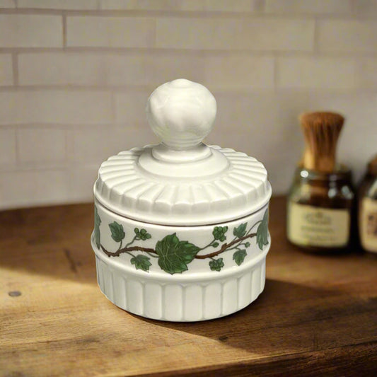 White decorative container with a lid and green leaf design.