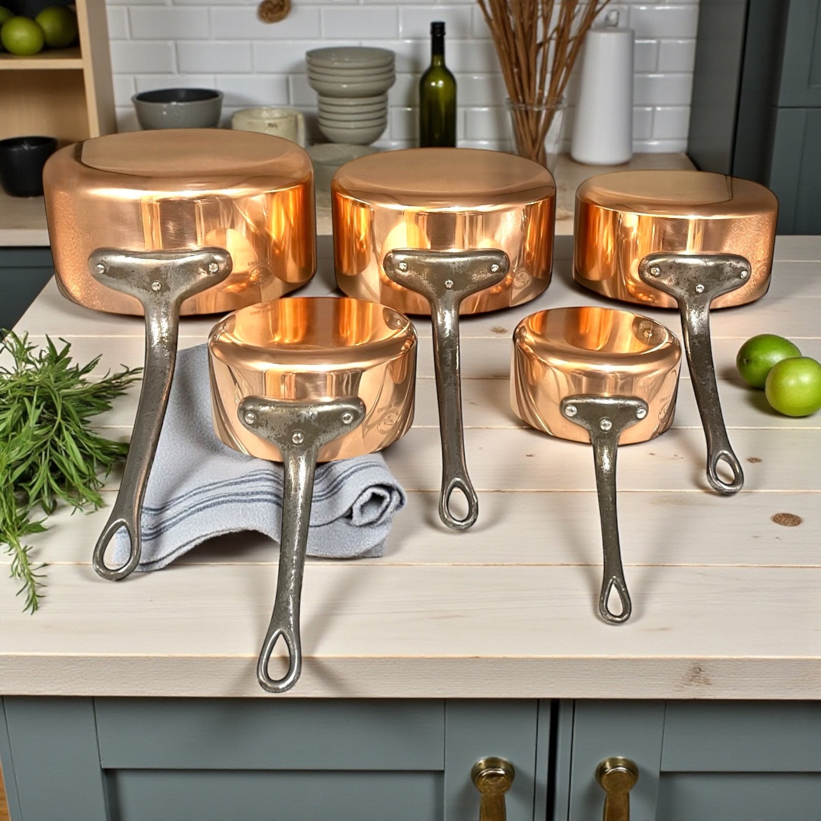 Set of copper cookware with grey handles on a kitchen counter.