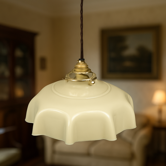 Vintage French milk glass pendant light with scalloped edge shade, brass gallery, and twisted brown fabric cord, rewired for UK use with a blurred period style lounge in the background