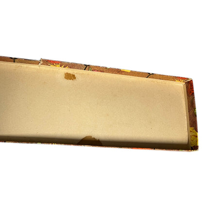 An open cardboard box interior with a light tan base and a patterned brown, red, and yellow lid edge, shown on a plain white background.