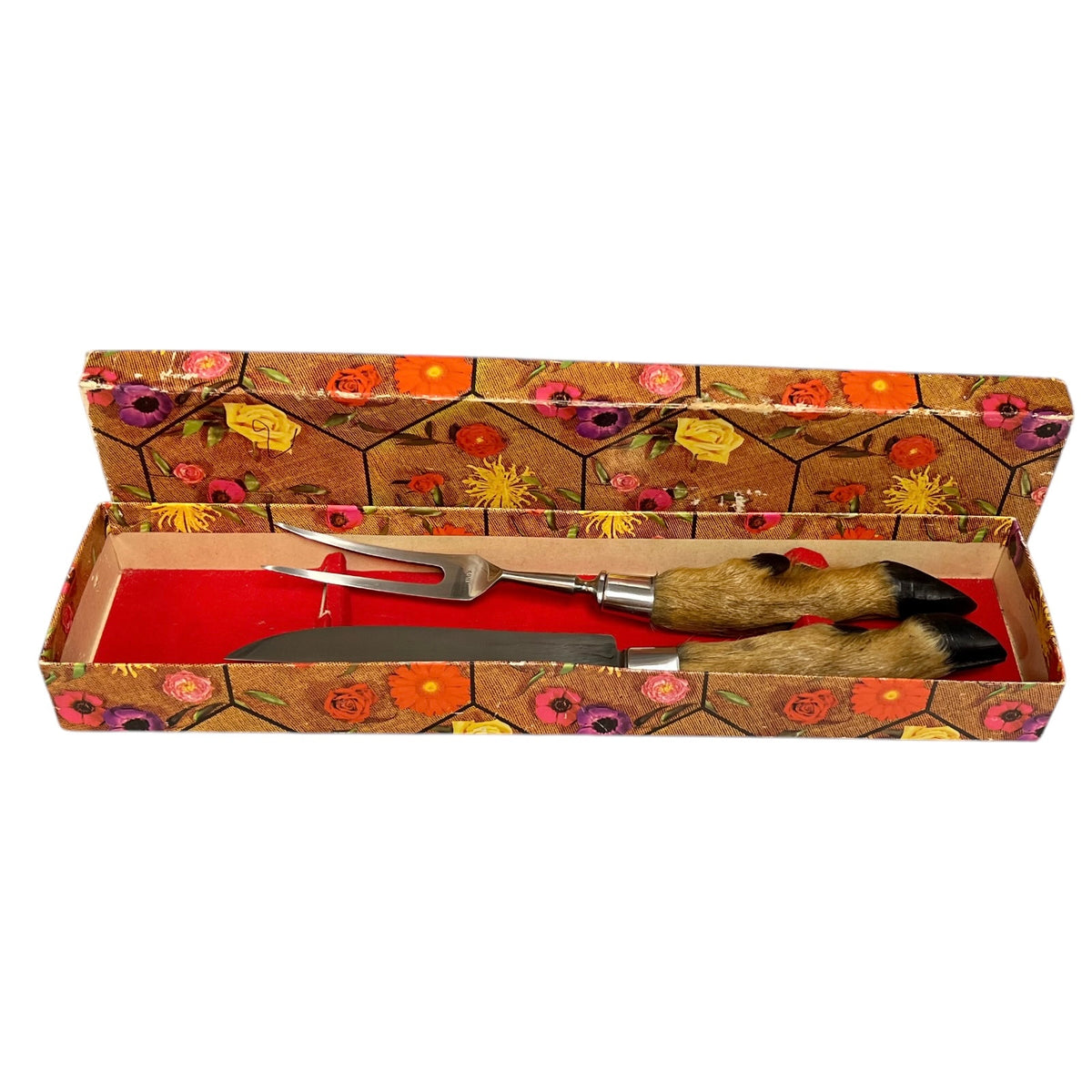 A decorative gift set containing a serving fork and knife in an open floral-patterned box with a red interior. The handles are made of animal fur with black tips, and the box lid features a colorful floral print on a brown background.