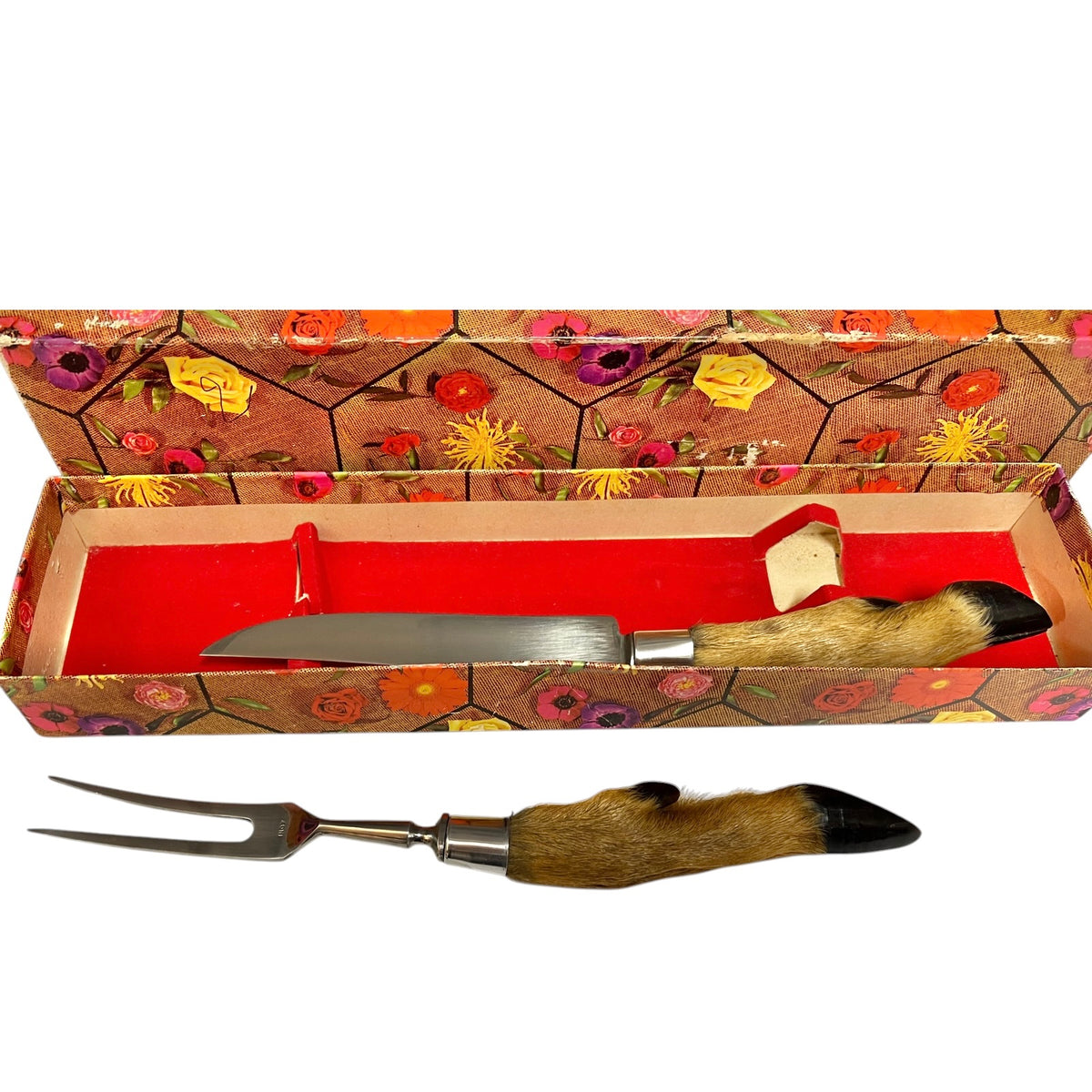 A two-piece serving utensil set consisting of a knife and a two-pronged fork, both featuring natural animal fur handles with black tips, displayed with their vintage floral-patterned presentation box on a white background.
