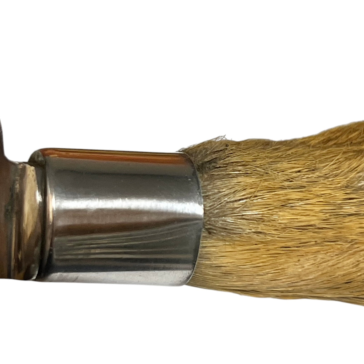 A close-up of a deer hoof handle showing a metallic silver ferrule and golden-brown bristles against a plain white background.