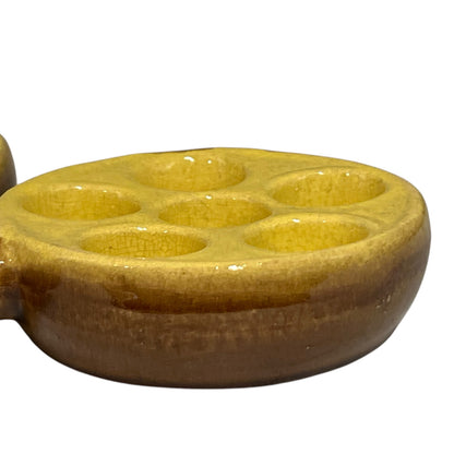 side view of a French vintage ceramic escargot serving plates, yellow inner with a brown exterior, each has 6 holes, shown on a white background 