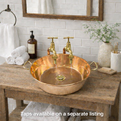 Copper up cycled basin sink with brass handles on a wooden vanity with taps 
