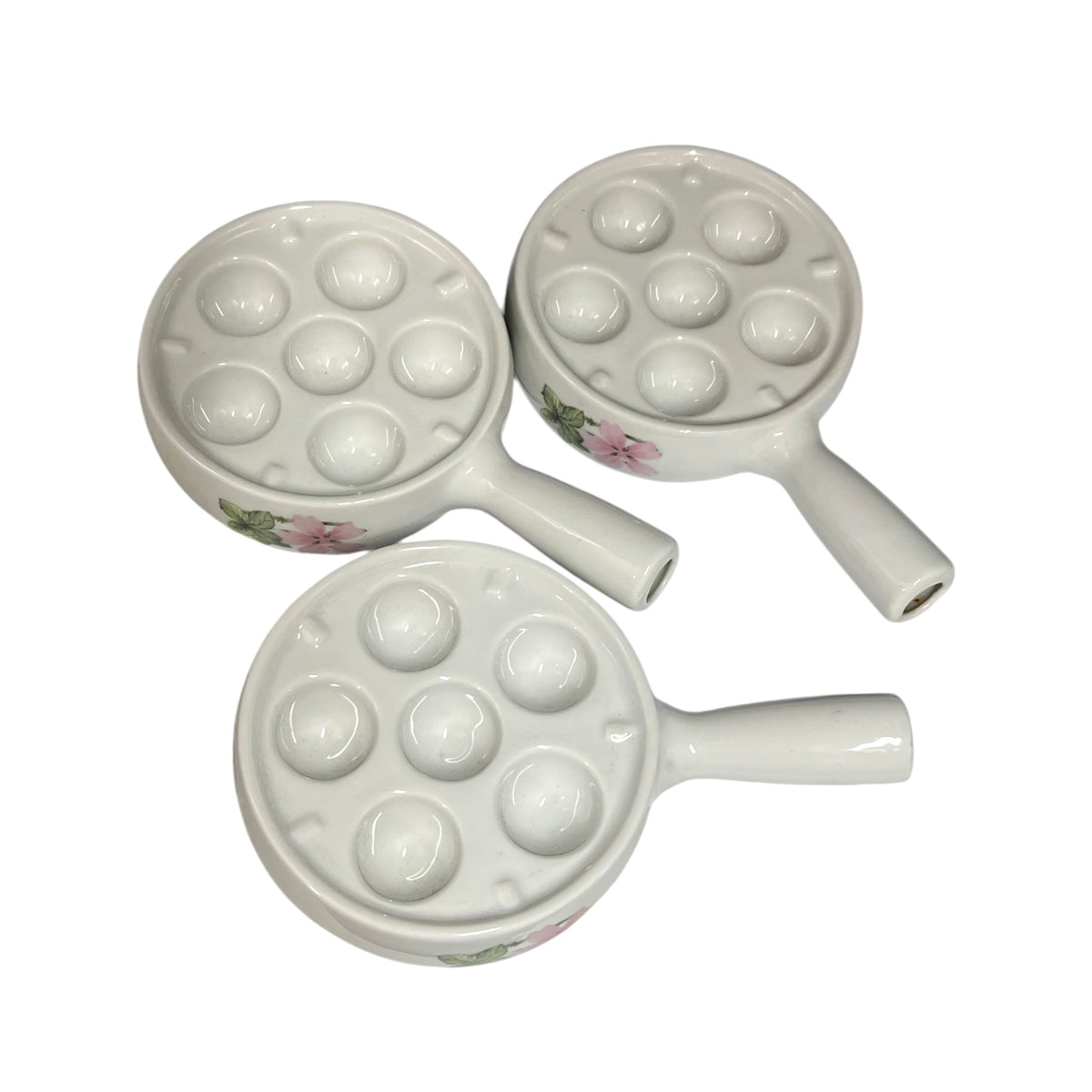 Three white ceramic escargot plates with floral pink and green accents, arranged on a plain white background.
