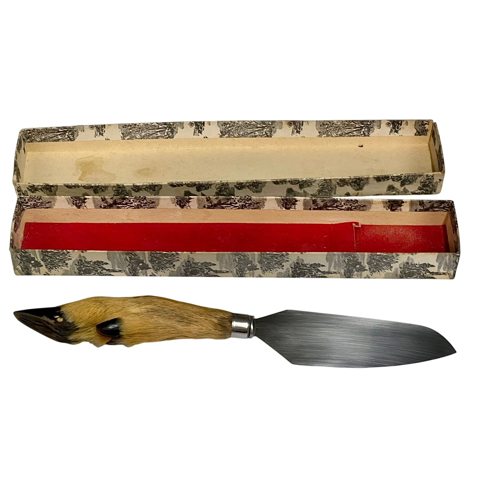 A vintage cake slice with a carved animal hide handle and a steel blade, displayed below its patterned presentation box with a red insert on a white background.