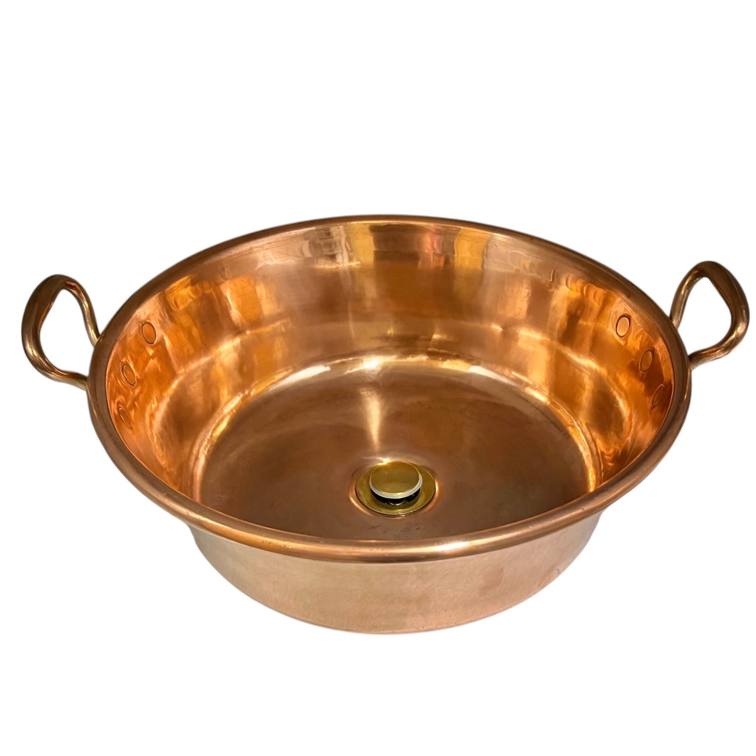 A round copper-colored metal basin or shallow pot with two loop handles on either side and a small brass drain at the bottom center, shown on a plain white background.