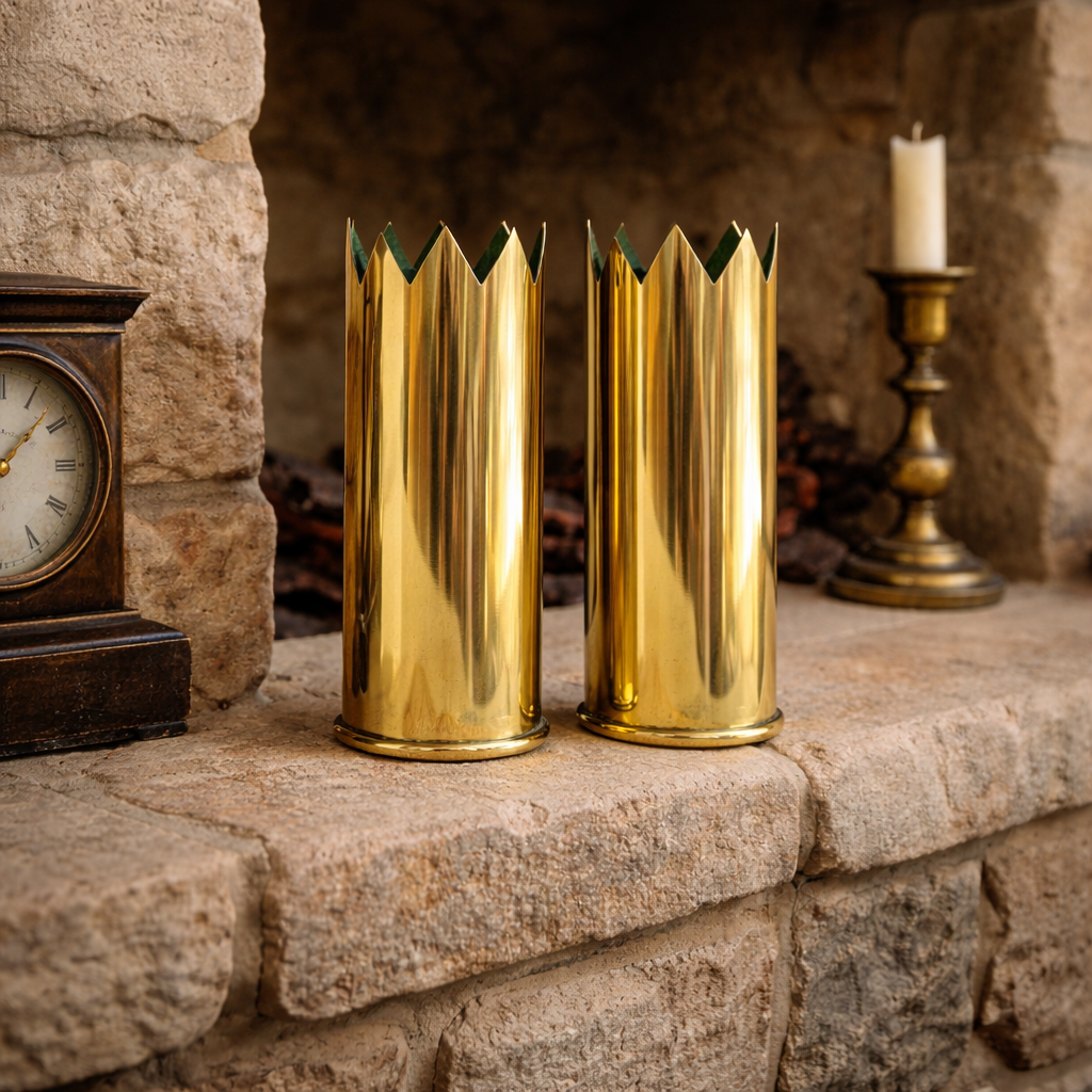 Two brass WW1 shells on a stone fireplace mantle with a clock and candle in the background.