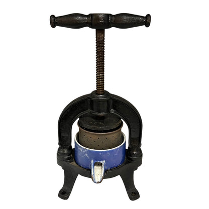 Vintage cast iron olive press with a blue container on a white background