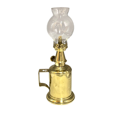 Brass oil lamp with clear glass shade on a white background