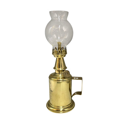 Brass oil lamp with a clear glass chimney on a white background