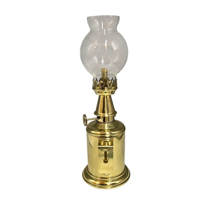 Brass oil lamp with a clear glass chimney on a white background
