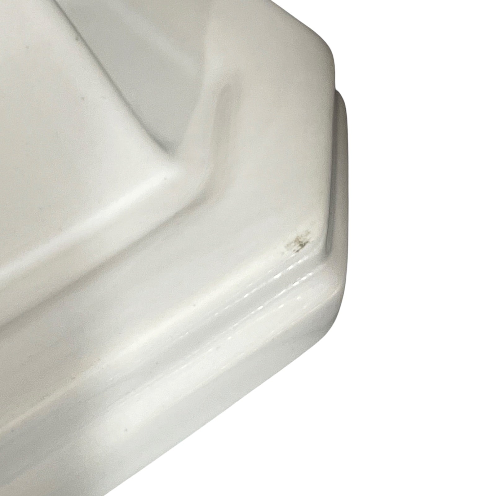 Close-up of a white ceramic shelf corner on a white background