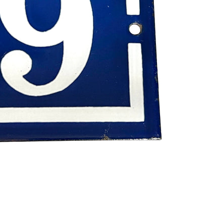 Close-up of a vintage French enamel door number against a white background.