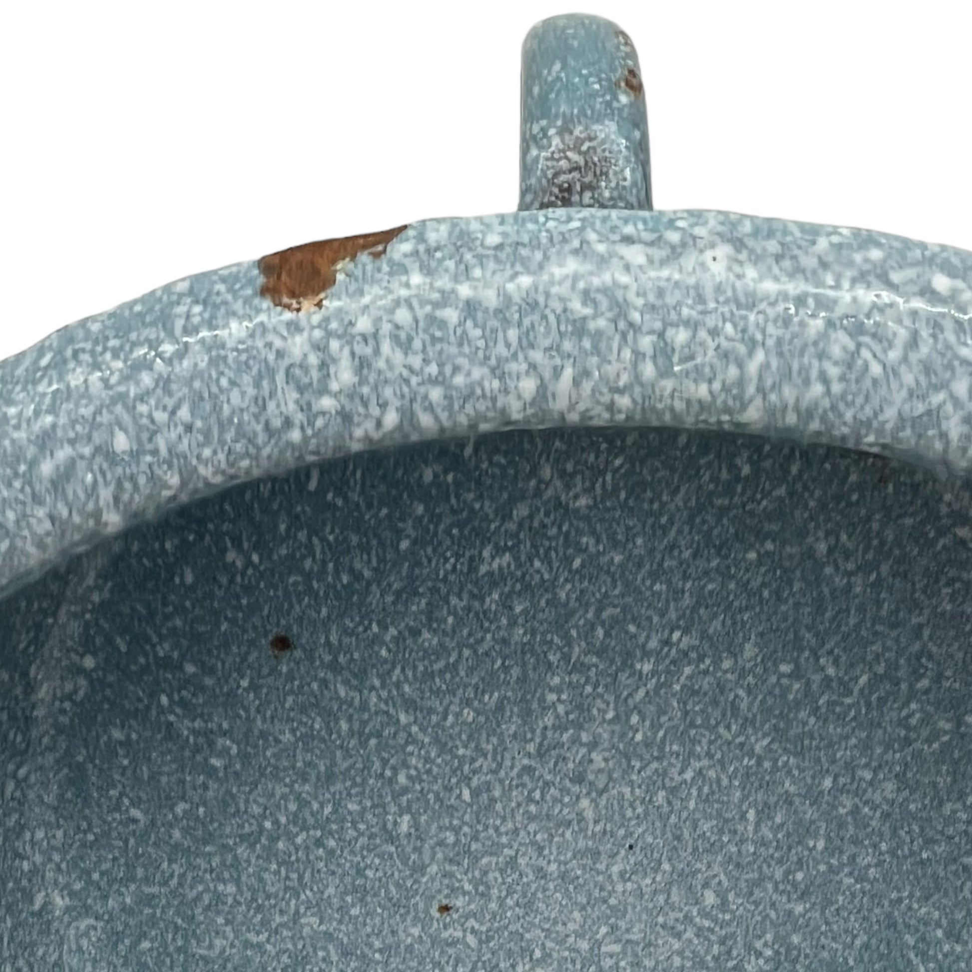 Close-up of wear and tear on a blue metal planter on a white background