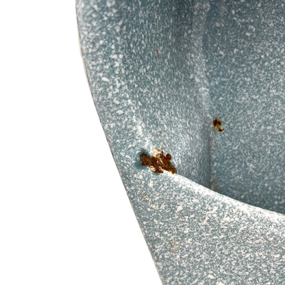 Close-up of wear and tear on a blue metal planter on a white background