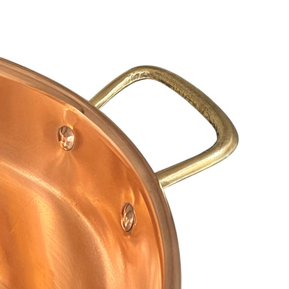Close-up of a copper pot with a brass handle on a white background