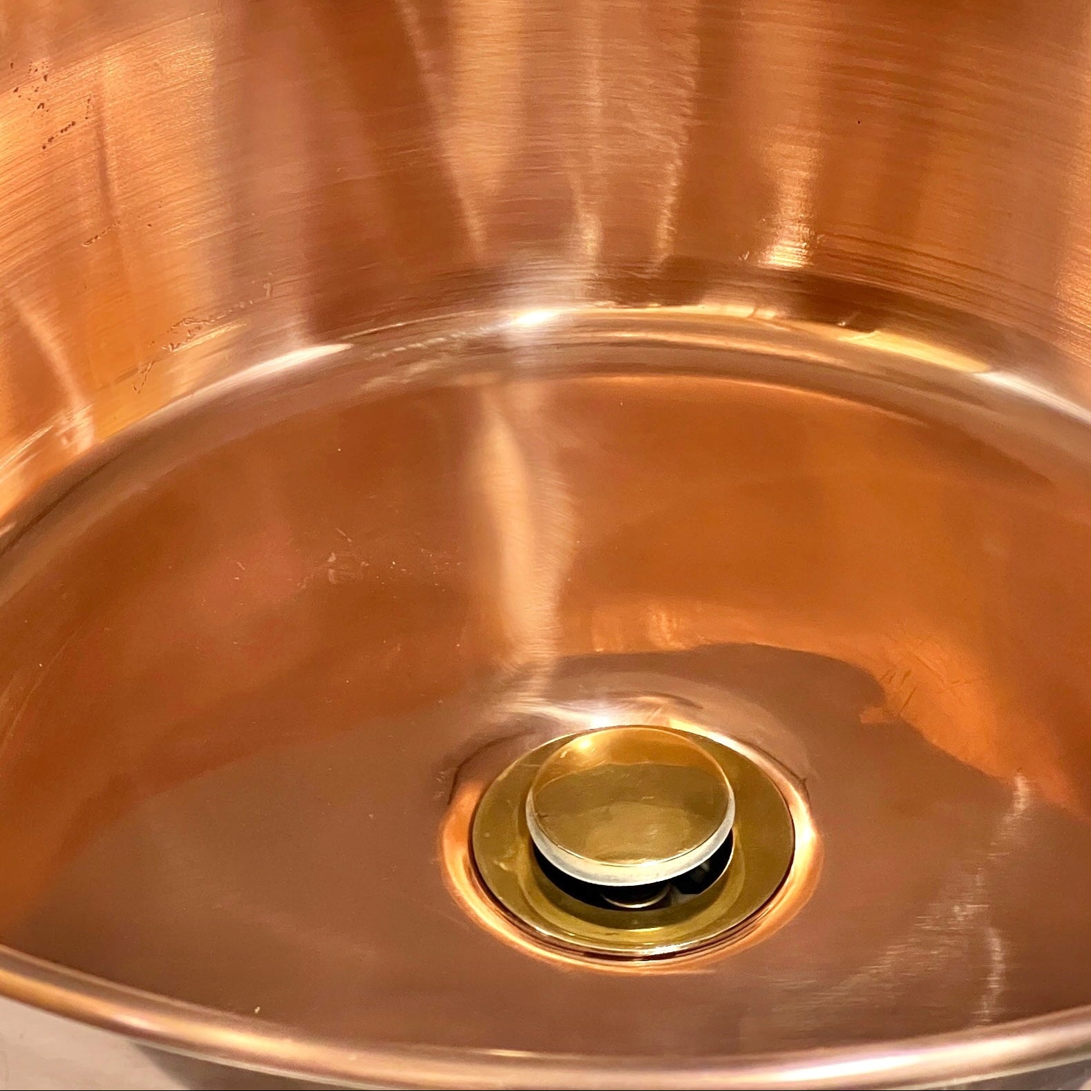 Close-up of a copper sink with a drain