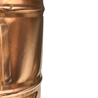 Close-up of a brass or copper cylindrical object with a textured surface on a white background