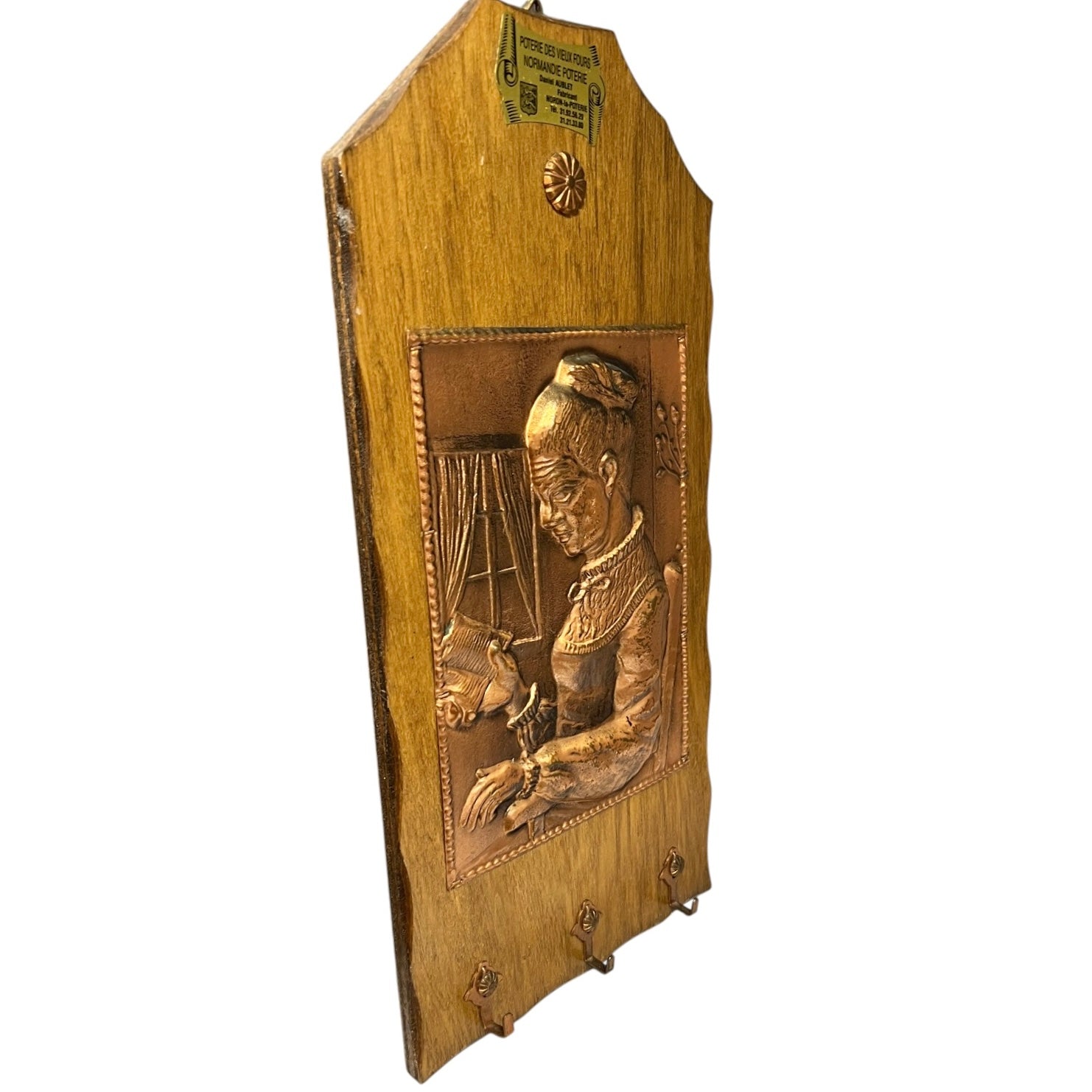 A vintage carved wooden wall plaque featuring a relief portrait of a woman, with three metal coat hooks at the bottom and a small decorative medallion near the top.