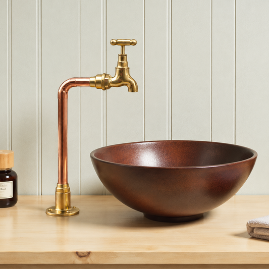 Brown sink with gold faucet on a wooden surface against a light wooden panel wall.