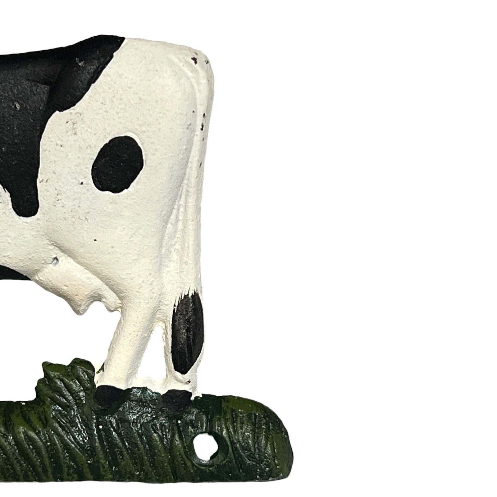 Black and white cow figure on a green base against a white background