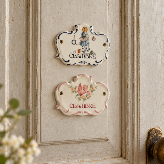 Pair of vintage French Limoges porcelain Chambre bedroom door plaques, one with blue boy design and one with pink floral design, displayed on a traditional cream-painted French country door with antique brass handle.